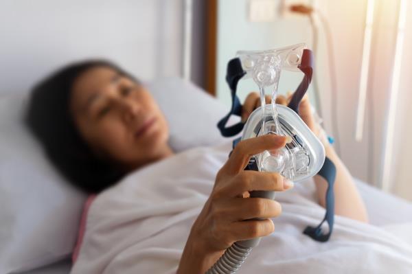 Senior patient woman hands holding Cpap mask in hospital room