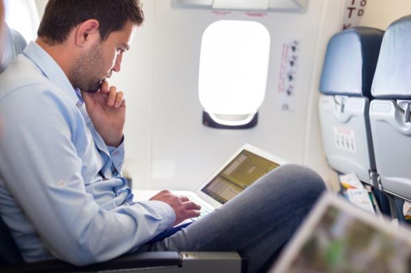 man working on laptop on airplane